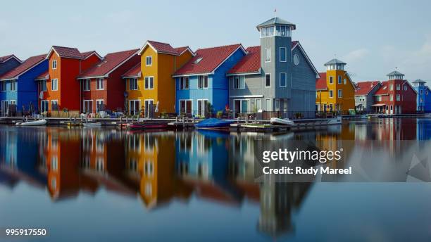 coloured buildings by a lake. - rudy stock-fotos und bilder