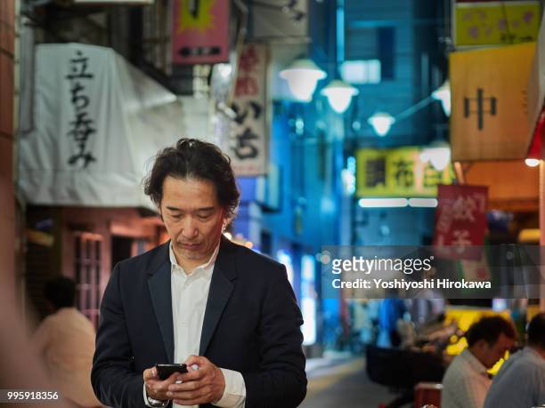 businessman walking alley with smartphone in twilight at tokyo - chofu 個照片及圖片檔