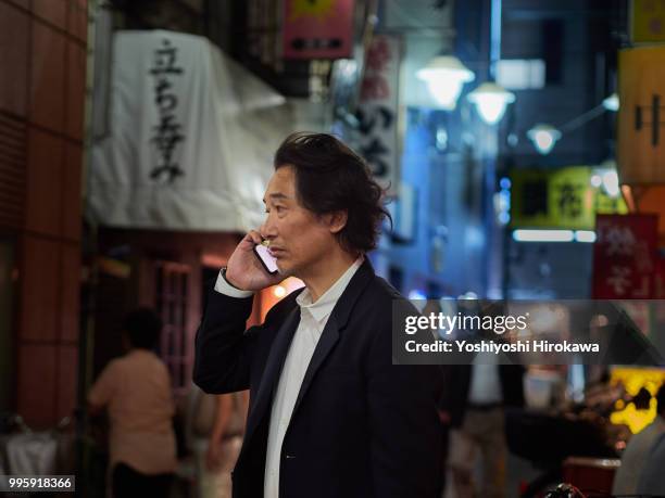 businessman calling with smartphone in twilight at tokyo - chofu stock-fotos und bilder