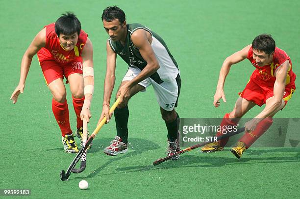 Pakistani field hockey player Muhmmaad Umar Bhutta is flanked by Chinese players Sun Zhixin and Meng Jun during their match in the Sultan Azlan Shah...