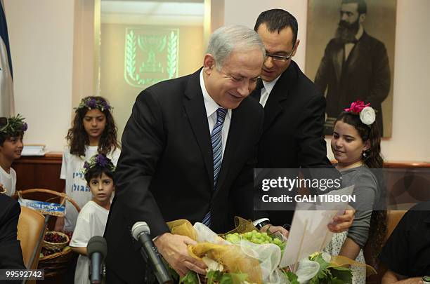 Israel's Prime Minister Benjamin Netanyahu holds a basket of grapes offered to him by Israeli children on the occasion of the Jewish feast of Shavout...