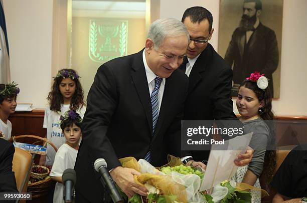 Israel's Prime Minister Benjamin Netanyahu holds a basket of grapes offered to him by Israeli children on the occasion of the Jewish feast of...
