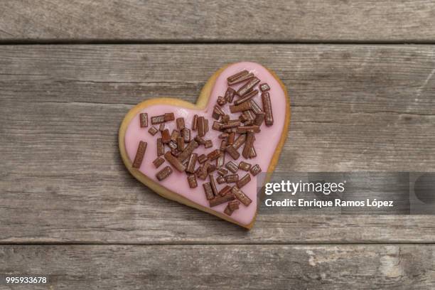 cookie covered with pink icing and chocolate chips - animal internal organ stockfoto's en -beelden