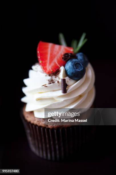 vanilla cupcake on black background - costume beige stock pictures, royalty-free photos & images