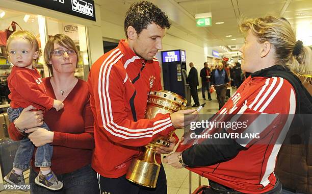 Bayern Munich's Dutch midfielder Mark van Bommel signs an autograph for a fan as he arrives at the airport in the southern German city of Munich...