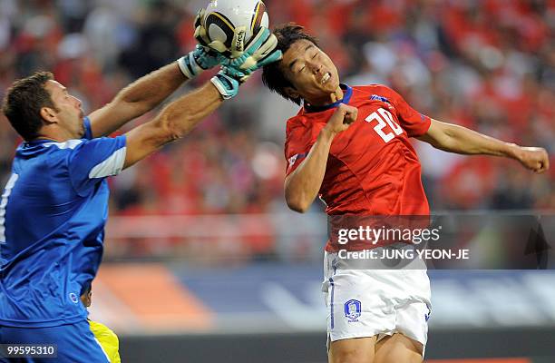 South Korea's Lee Dong-Gook jumps for the ball as Ecuador's goalkeeper Marcelo Elizaga catches the ball during a friendly football match in Seoul on...