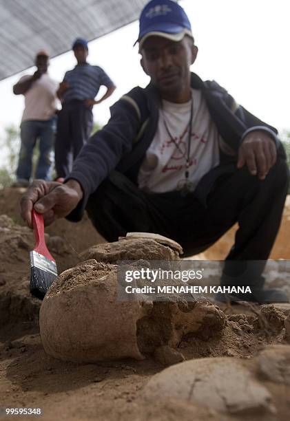 Worker of Israel's Antiquities Authority brushes dirt off a skull found in ancient graves near the Barzilai hospital in the southern Israeli city of...