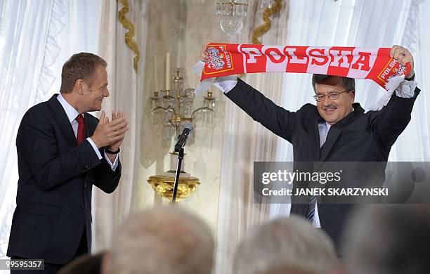 Acting President of Poland Bronislaw Komorowski holds up a football fan scarf he received from Prime Minister Donald Tusk during a meeting with his...