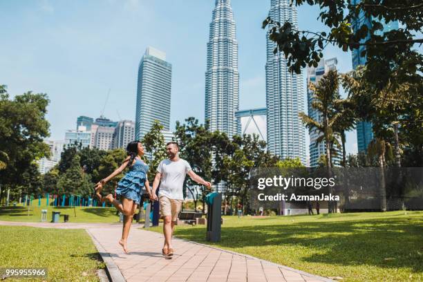 woman walking barefoot with her boyfriend in kuala lumpur - kuala lumpur stock pictures, royalty-free photos & images