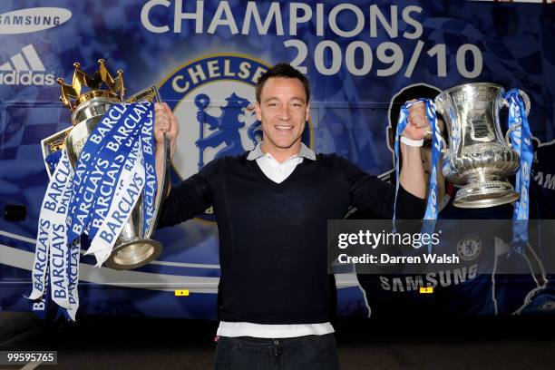 John Terry of Chelsea poses with the Premier League and FA Cup trophies prior to the Chelsea Football Club Victory Parade on May 16, 2010 in London,...