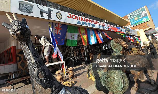 West African curios vendor puts up the flags of the 32 nations which will take part in the World Cup, in front of his shop in Johannesburg on May 16,...