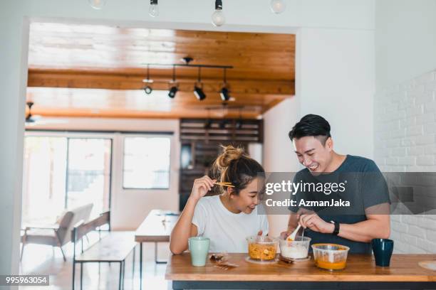 chinese couple eating noodles in domestic kitchen - young adult couple stock pictures, royalty-free photos & images