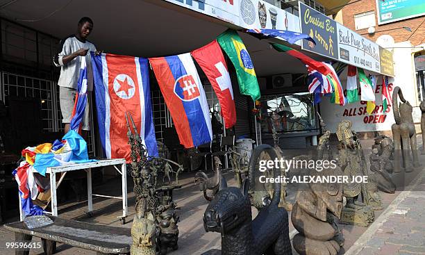 West African curios vendour puts up flags in front of his shop in Johannesburg on May 16 of the 32 nations which are taking part in the FIFA World...