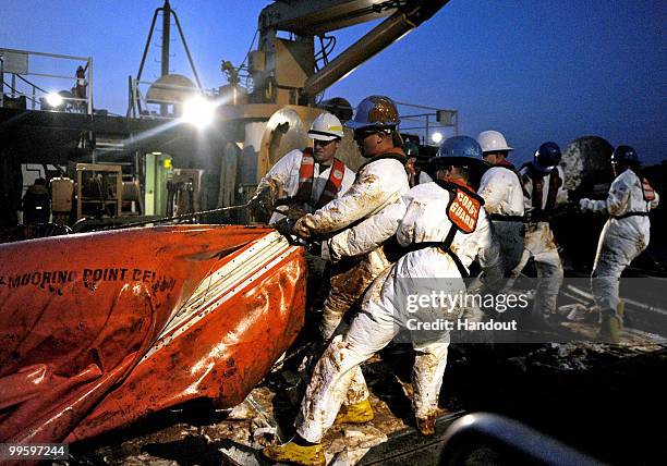 In this handout from the U.S. Department of Defense, crewmembers from USCGC Harry Claiborne remove an oil covered boom from the ocean May 8, 2010 in...