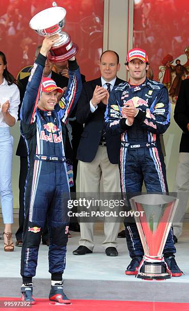 Red Bull's German driver Sebastian Vettel celebrates on the podium as Red Bull's Australian driver Mark Webber and Prince Albert of Monaco applaud on...