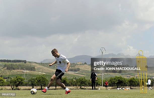 Germany's striker Lukas Podolski runs with the ball during a training session at the Verdura Golf and Spa resort, near Sciacca May 16, 2010. The...