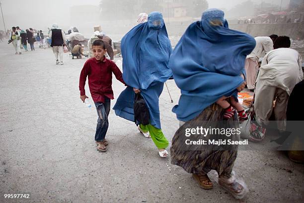 People protect themselves from the wind on commercial street during a sandstorm that followed a severe rain storm on May 16, 2010 in Kabul,...