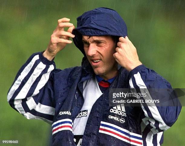 French national soccer team defender Laurent Blanc covers his head during a rainy training session 14 June in Clairefontaine, outside Paris, where...