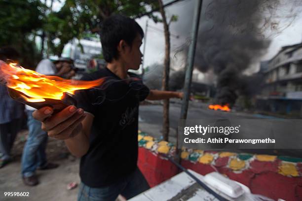 An anti-government protester 'Red Shirt' throws a molotov cocktail toward Thai security forces as the violence in central Bangkok continues on May...
