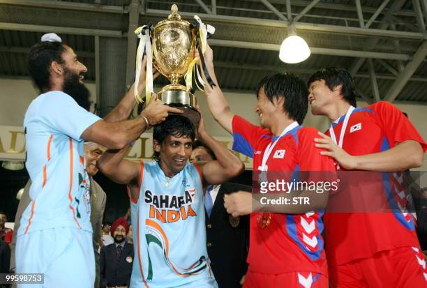 India's Arjun Halappa carries the trophy over his head while Indian captain Rajpal Singh , South Korea's Kim Yong-bae , and Ro Jong-hwan assist...