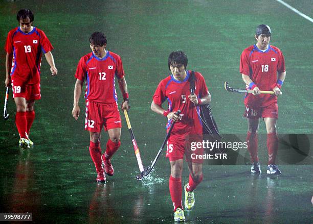 South Korean field hockey players leave the pitch amid heavy rain following their final match against India during the 19th Sultan Azlan Shah Cup...