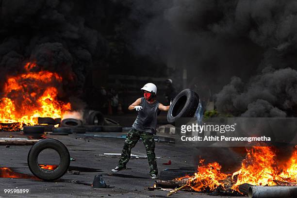 Anti-government protester 'Red Shirt' adds to a burning tires as the violence in central Bangkok continues on May 16, 2010 in Bangkok, Thailand. So...