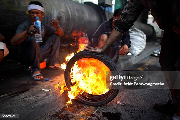 Anti-government protester 'Red Shirt' adds to a burning tires as the violence in central Bangkok continues on May 16, 2010 in Bangkok, Thailand. So...