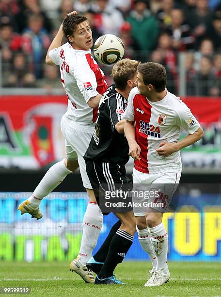Mike Frantz of Nuernberg is challenged by Jens Hegeler and Daniel Baier of Augsburg during the Bundesliga play off leg two match between FC Augsburg...