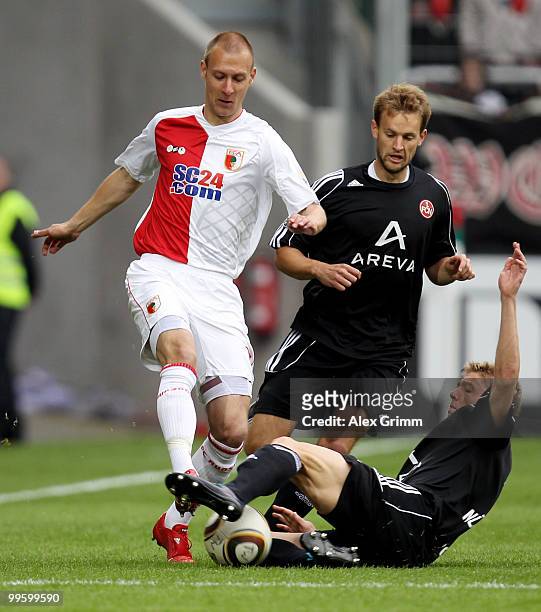 Dominik Reinhardt of Augsburg is challenged by Pascal Bieler and Mike Frantz of Nuernberg during the Bundesliga play off leg two match between FC...