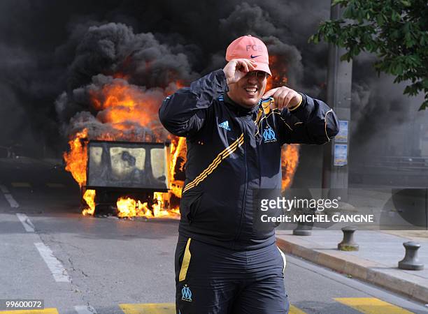 An Olympique de Marseille supporter walks away from a dustbin on fire, on May 16, 2010 in Marseille southern France, where a few incidents broke out...