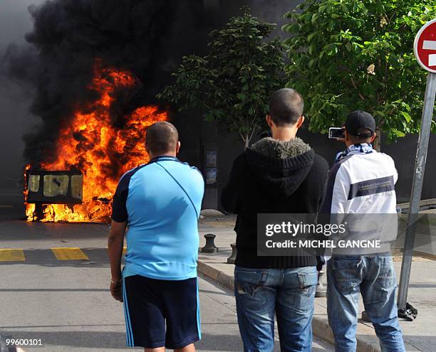 Three men watch a dustbin on fire, on May 16, 2010 in Marseille southern France, where a few incidents broke out after Olympique de Marseille's...