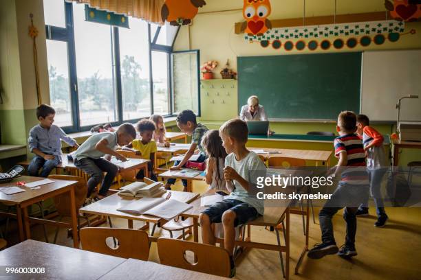 large group of elementary students having fun on a class in the classroom. - naughty in class stock pictures, royalty-free photos & images