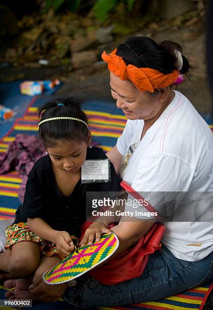 Girl with a piece of paper with his personal details sits in the lap of a woman at Wat Pathum Wanaram on May 16, 2010 in Bangkok, Thailand. The...