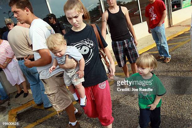 Kathryn Nelson walks with her children Hunter Nelson and Steven Hunter after collecting a number to reserve a spot in line for filing claims against...