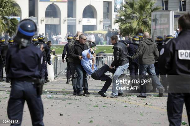 Man is arrested by two policemen in civilian clothes as French anti-riot police forces face Olympique de Marseille supporters on May 16, 2010 in...