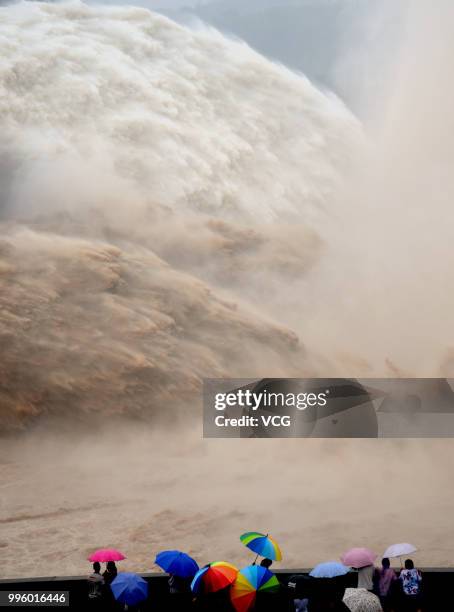 People watch as water and sand is blasted from the Xiaolangdi Dam on the Yellow River on July 4, 2018 in Jiyuan, Henan Province of China. A round of...