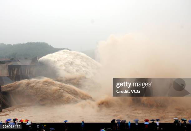 People watch as water and sand is blasted from the Xiaolangdi Dam on the Yellow River on July 4, 2018 in Jiyuan, Henan Province of China. A round of...