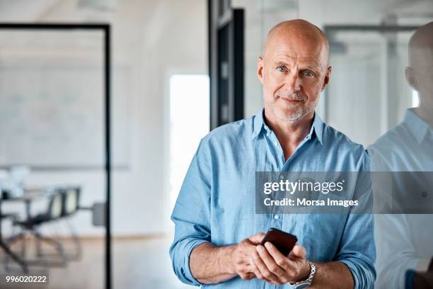 portrait of businessman with smart phone at office - completely bald stock pictures, royalty-free photos & images