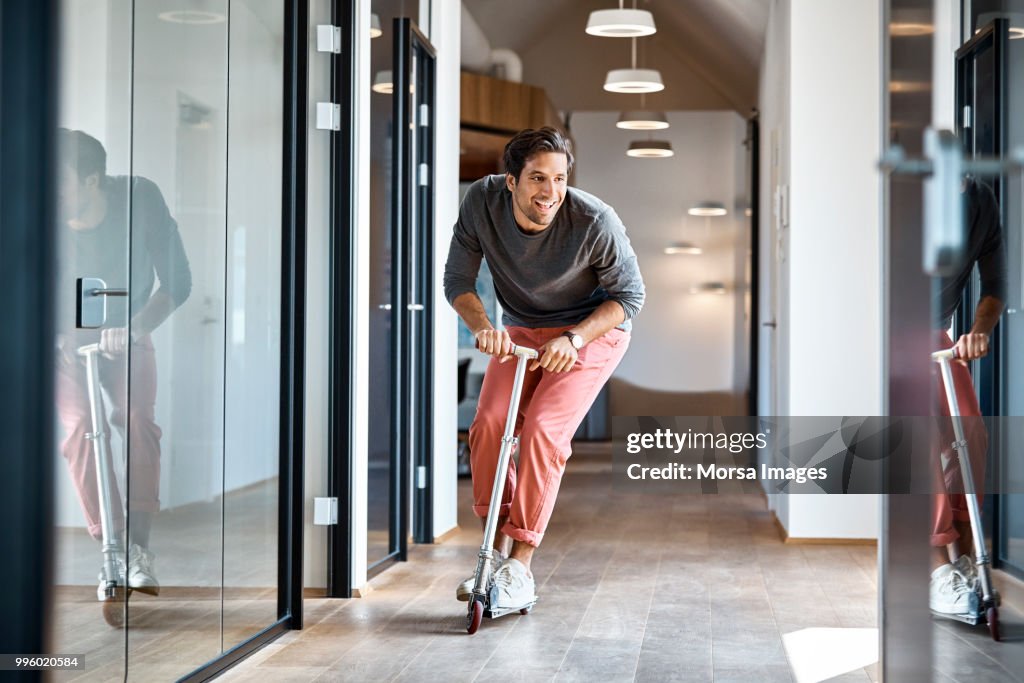 Businessman enjoying on push scooter in office