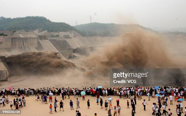 People watch as water and sand is blasted from the Xiaolangdi Dam on the Yellow River on July 8, 2018 in Jiyuan, Henan Province of China. The number...