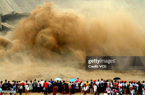 People watch as water and sand is blasted from the Xiaolangdi Dam on the Yellow River on July 8, 2018 in Jiyuan, Henan Province of China. The number...