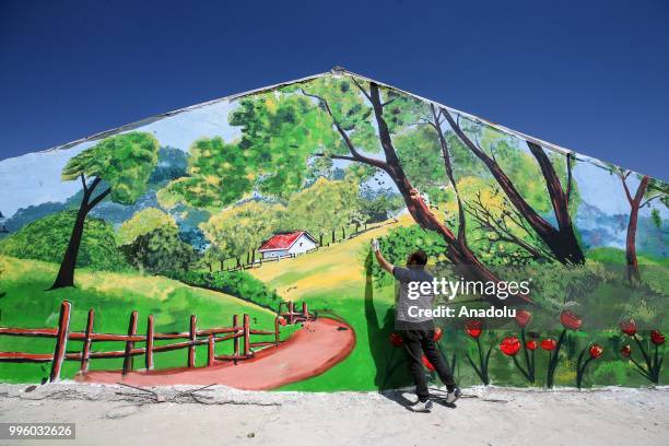 Painter paints a picture on a wall on the purpose of the reflecting Van's natural beauties in Van, Turkey on July 11, 2018. Van's Baskale...