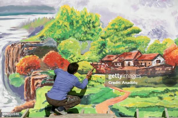 Painter paints a picture on a wall on the purpose of the reflecting Van's natural beauties in Van, Turkey on July 11, 2018. Van's Baskale...