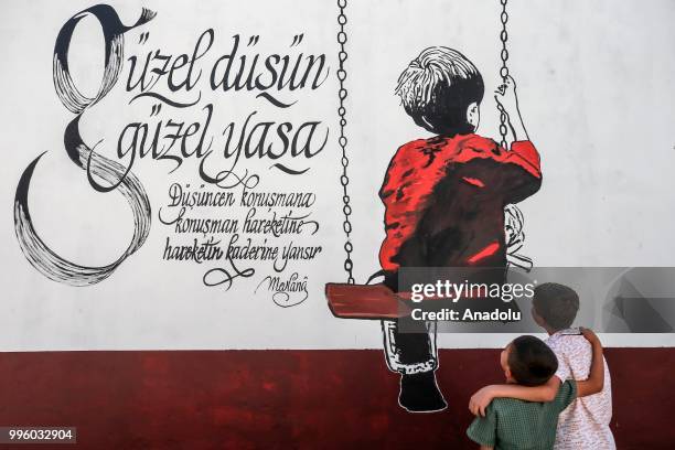 Children are seen in front of a painted wall which painted by painters on the purpose of the reflecting Van's natural beauties in Van, Turkey on July...