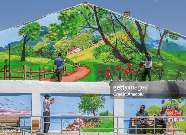 People are seen in front of a painted wall which painted by painters on the purpose of the reflecting Van's natural beauties in Van, Turkey on July...
