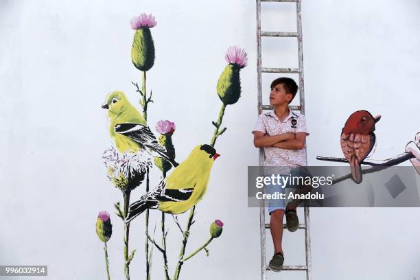 Child is seen on a ladder near a painted wall which painted by painters on the purpose of the reflecting Van's natural beauties in Van, Turkey on...