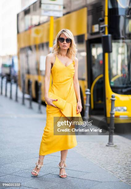 Gitta Banko wearing a yellow, draped dress by Jacquemus, yellow stingray leather clutch and asymmetric-geometrical shaped earrings by a cuckoo...