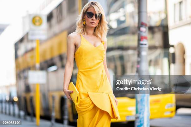 Gitta Banko wearing a yellow, draped dress by Jacquemus, yellow stingray leather clutch and asymmetric-geometrical shaped earrings by a cuckoo...