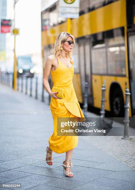 Gitta Banko wearing a yellow, draped dress by Jacquemus, yellow stingray leather clutch and asymmetric-geometrical shaped earrings by a cuckoo...