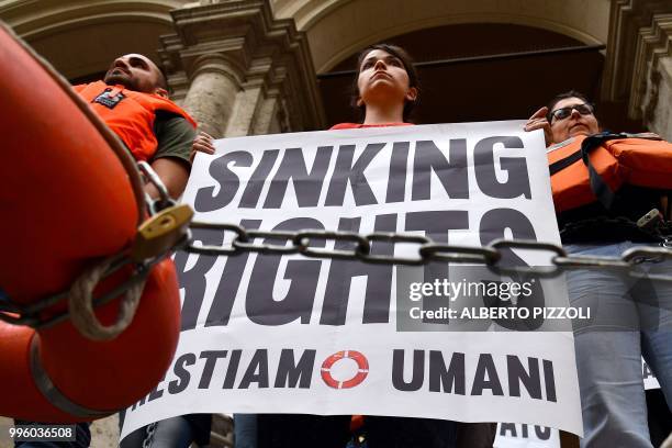 "We remain human" network activists hold banners reading "Sinking rights" as they are chained on the steps of the Ministry of Transport to protest...